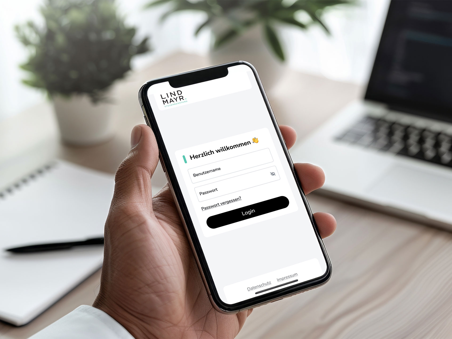 Eine Hand hält ein Smartphone. Darauf ist die Login-Seite von Lindmayr.Tax zu sehen.